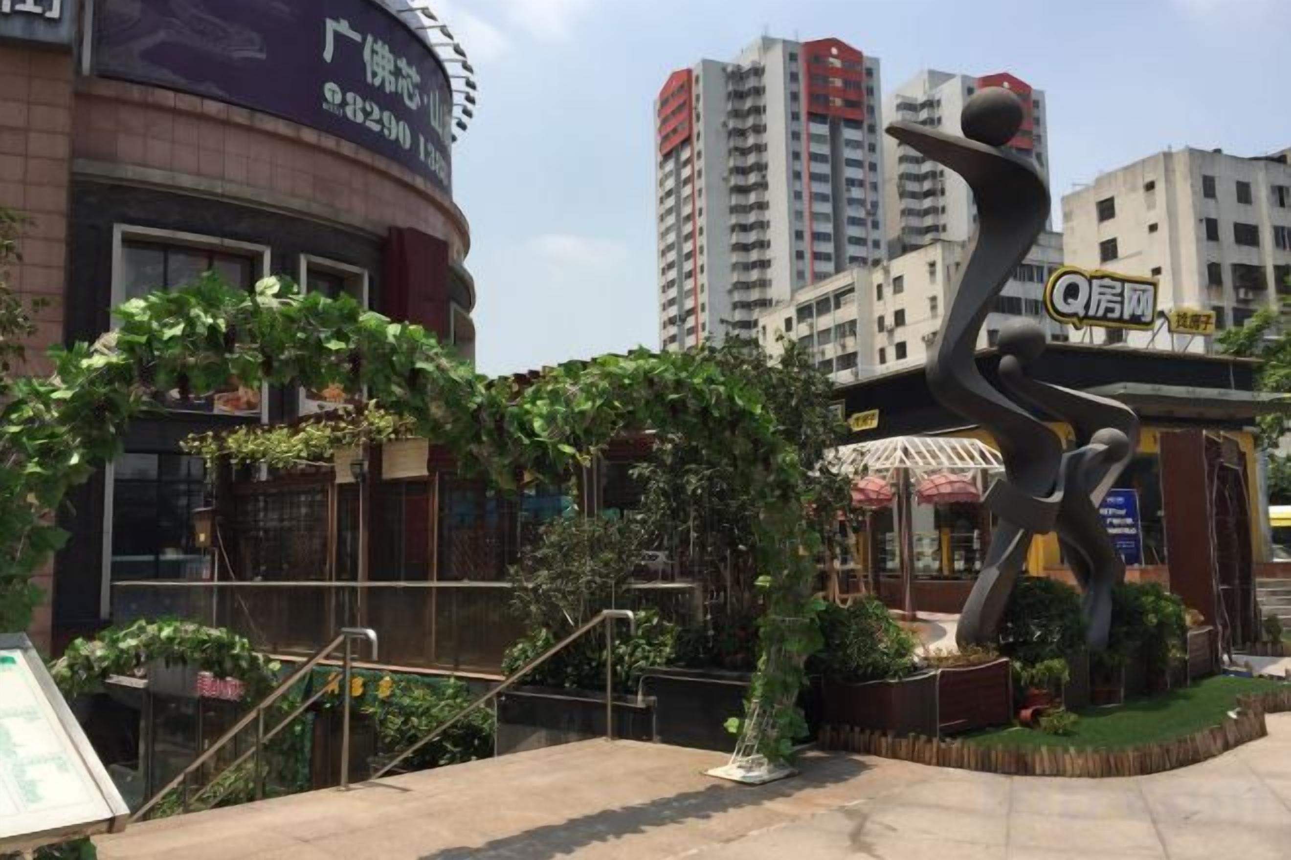 A public space with a sculpture, a building with signage, and a staircase.