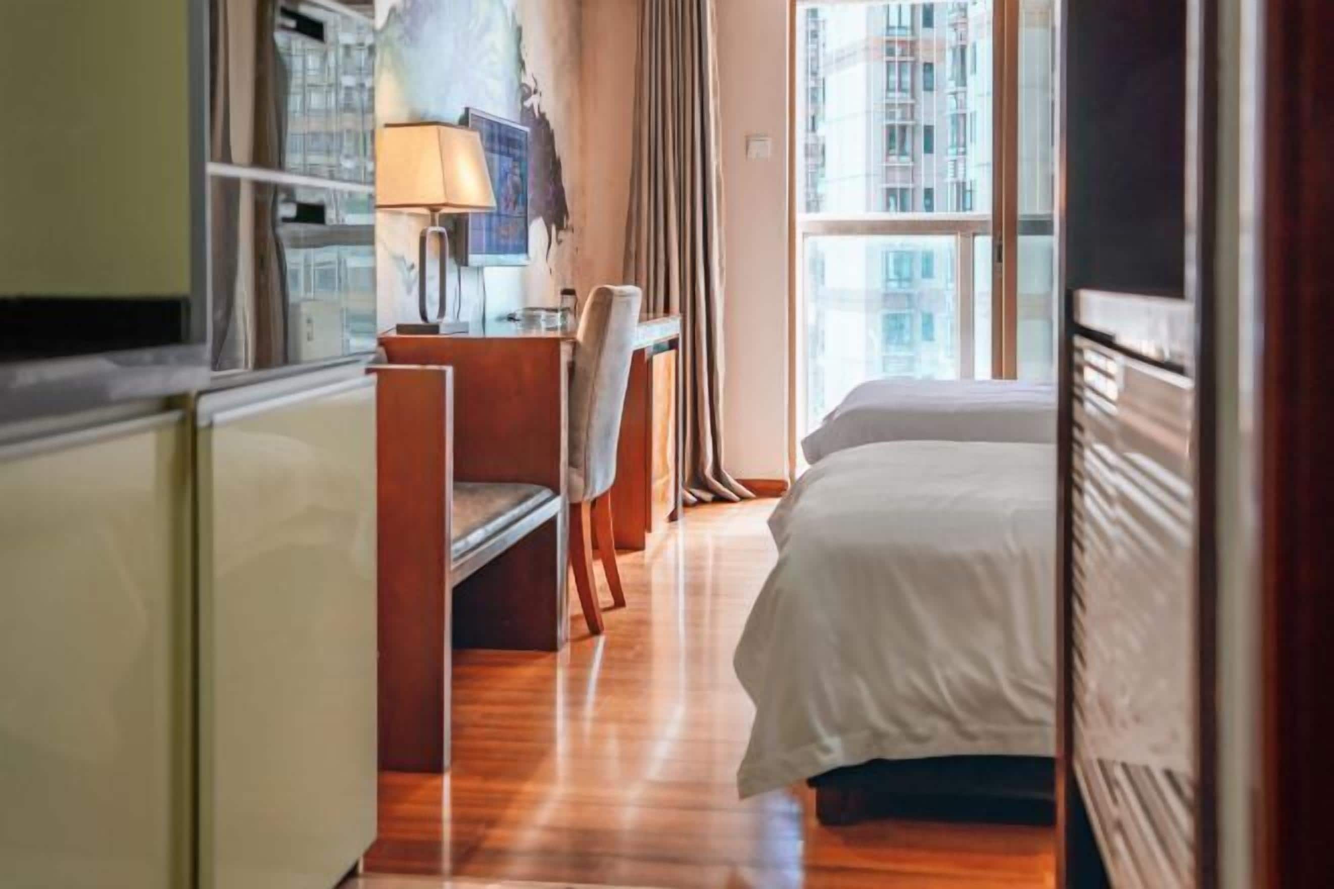 Habitación de hotel con cama, escritorio, silla y ventana con vistas a la ciudad.