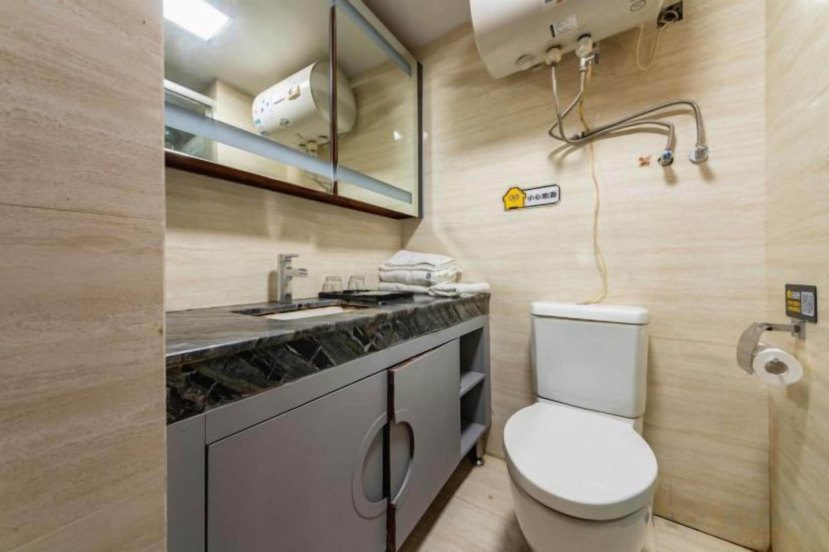 A bathroom with a toilet, sink, mirror, and towel rack.