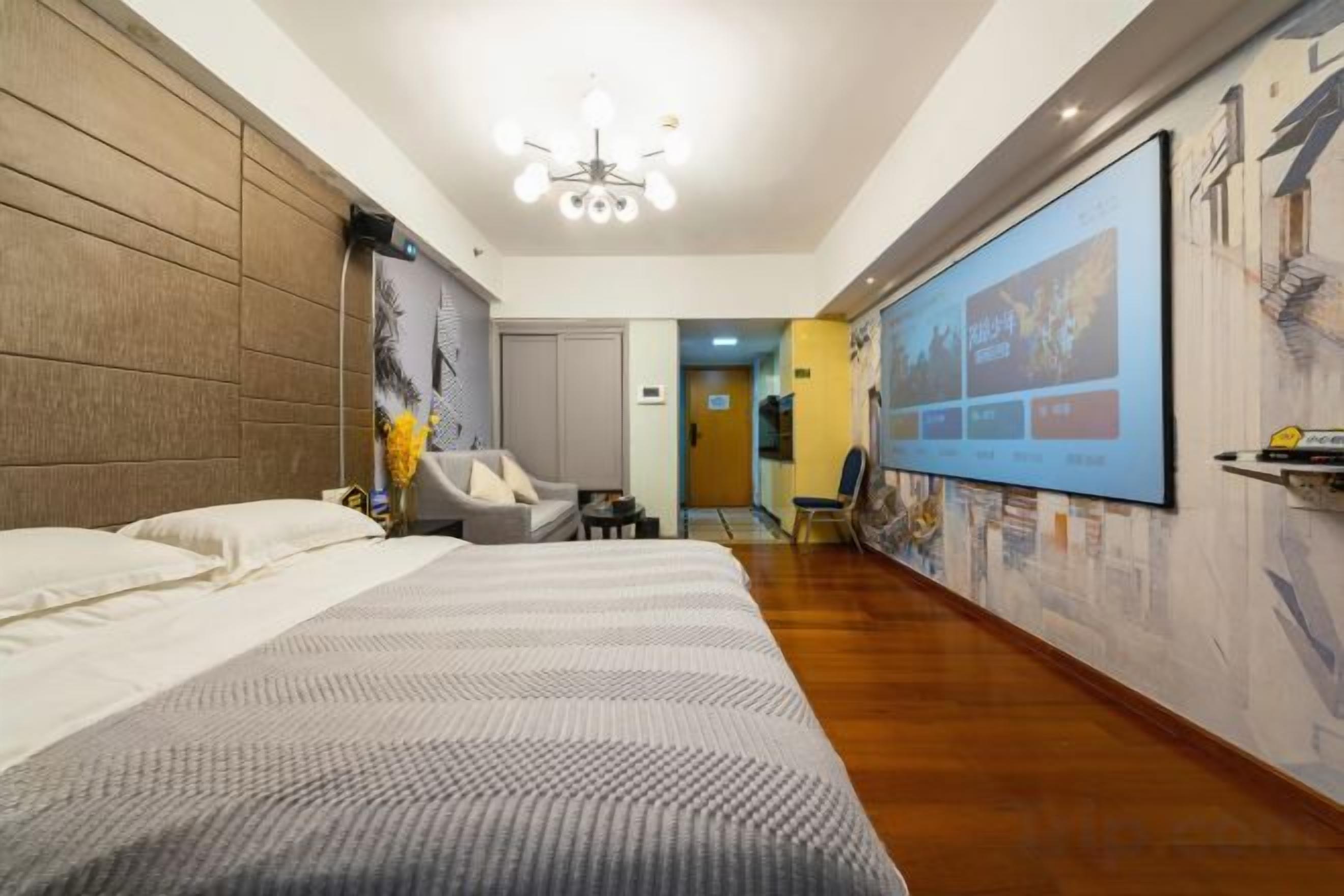 A hotel room with a large bed, a desk, a chair, and a wall-mounted TV.