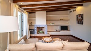 A living room with a fireplace, wooden beams, a sofa, and a television. - Casa la Concha - Marbellamar (Marbella)