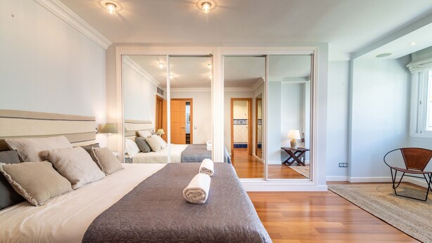A hotel room with a large bed, a sliding glass door leading to a balcony, and a small table with a chair. - Casa la Concha - Marbellamar (Marbella)