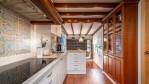 A kitchen with a central island, white cabinets, wooden beams, and a tiled backsplash. - Casa la Concha - Marbellamar (Marbella)