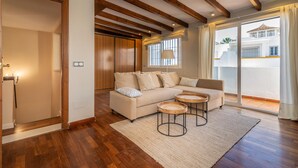 A modern living room with a wooden ceiling, a beige sofa, two round coffee tables, and a large sliding glass door leading to a balcony. - Casa la Concha - Marbellamar (Marbella)