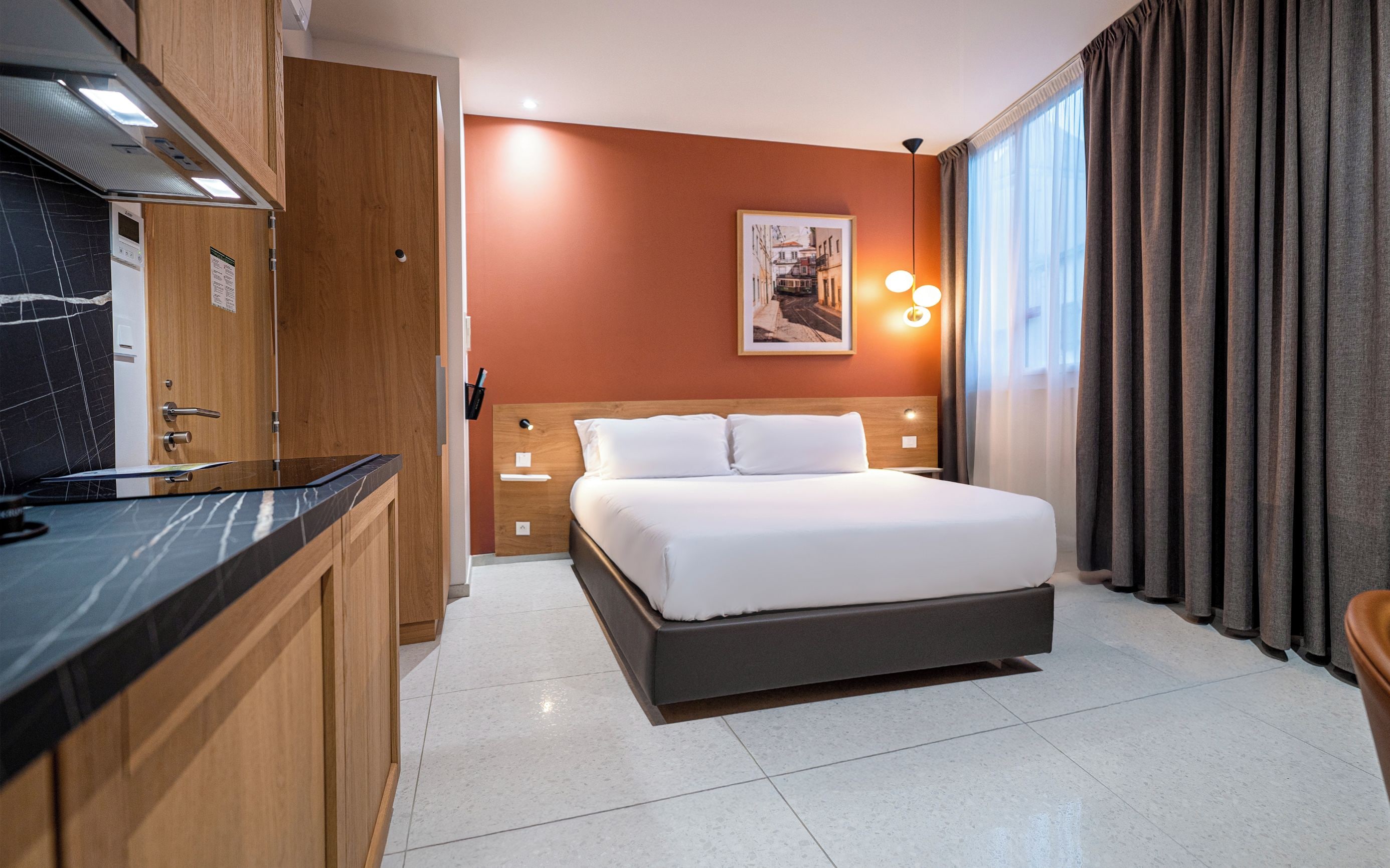 Ein modernes Hotelzimmer mit Bett, kleinem Schreibtisch, Spiegel und einem Bild an der Wand.