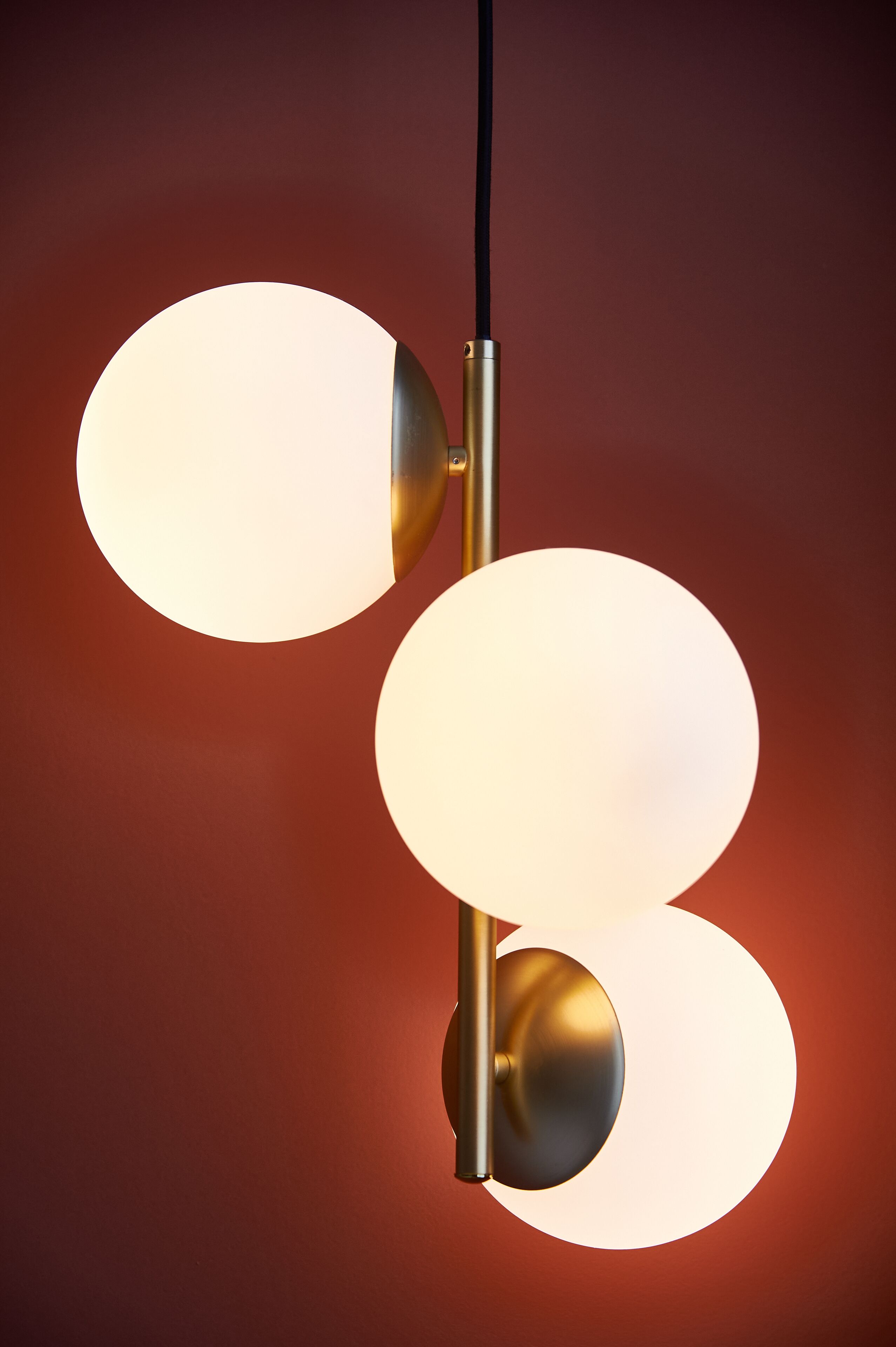A modern pendant light fixture with three spherical glass shades.