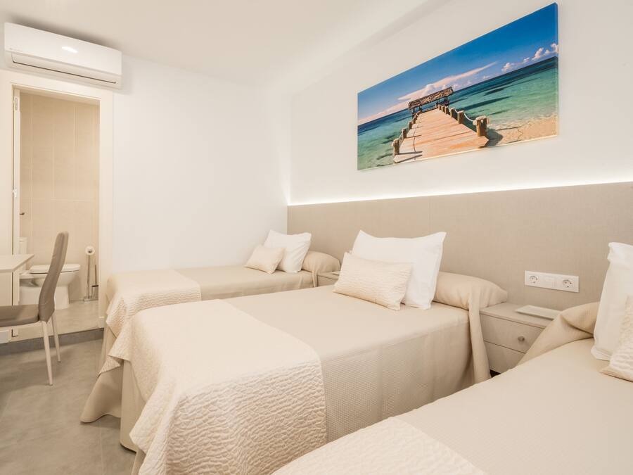 Habitació d'hotel amb dos llits, una taula de treball, una cadira i un quadre amb una escena de platja.
