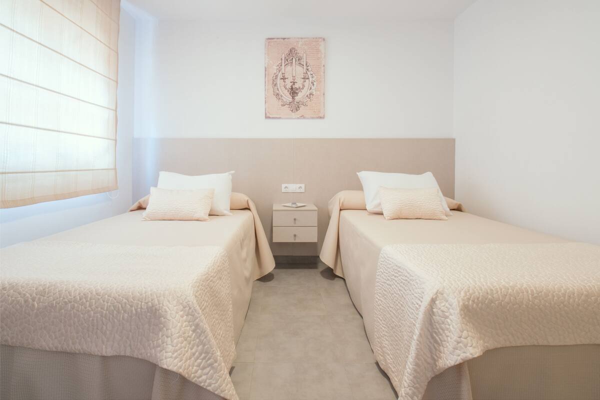 A twin room with two beds, a nightstand, and a wall-mounted artwork.