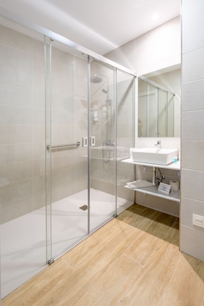 A modern bathroom with a glass-enclosed shower, a white sink, and a mirror above the sink.