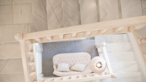 Un espacio de descanso pequeño y cerrado, con un banco acolchado y una sola silla, rodeado por un marco decorativo.