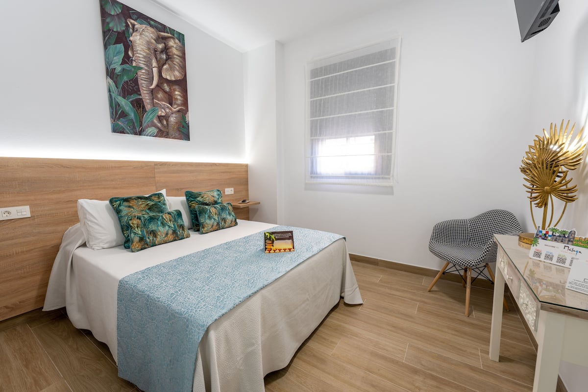 A modern hotel room with a bed, a desk, and a chair.