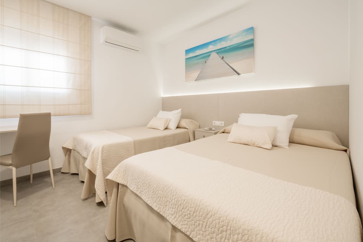 A hotel room with two beds, a desk, and a chair.
