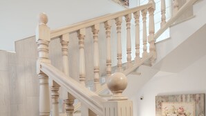 Una escalera de madera con balaustres y barandilla, que conduce a un piso superior.