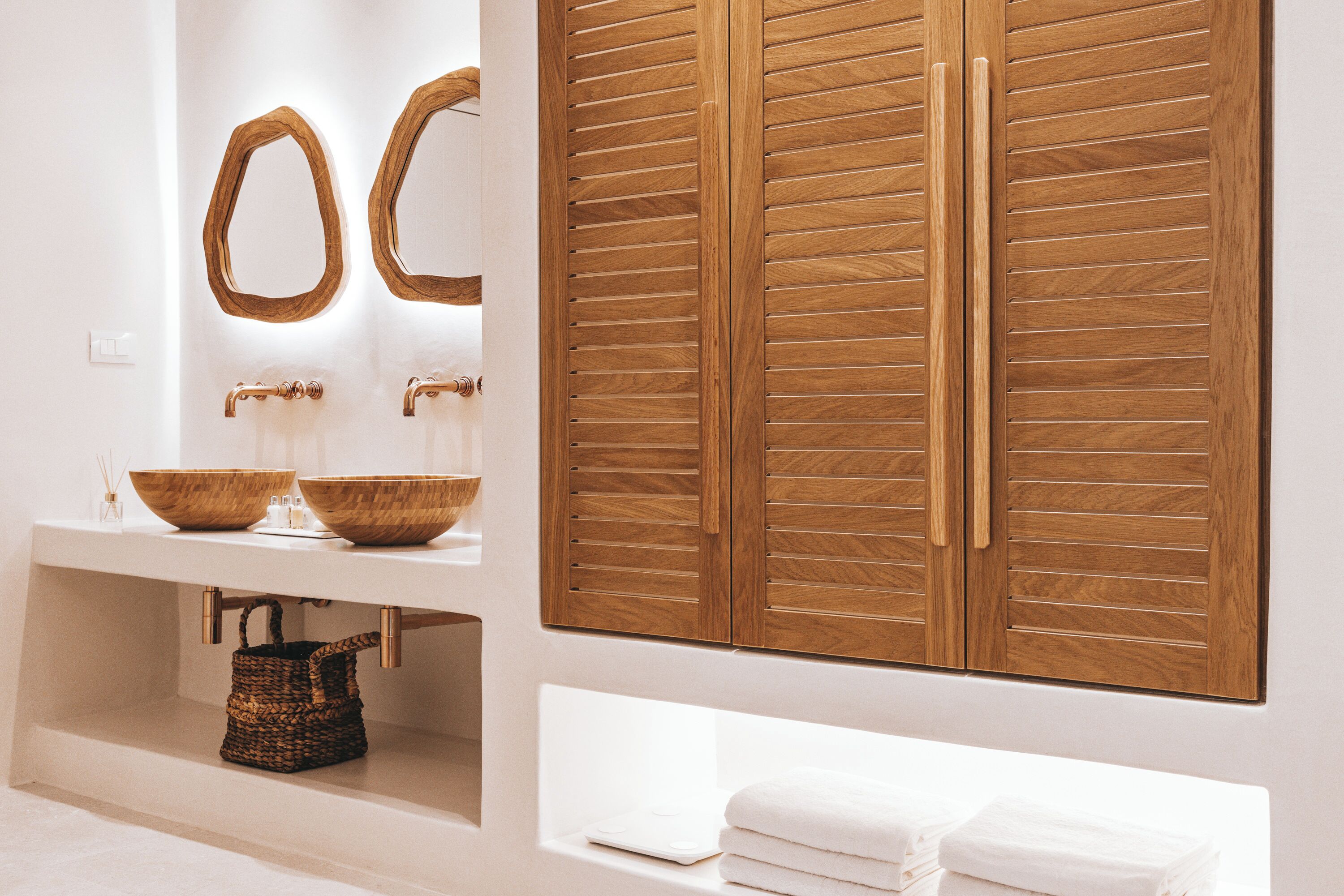 A bathroom with a wooden vanity, two sinks, and a large wooden door.