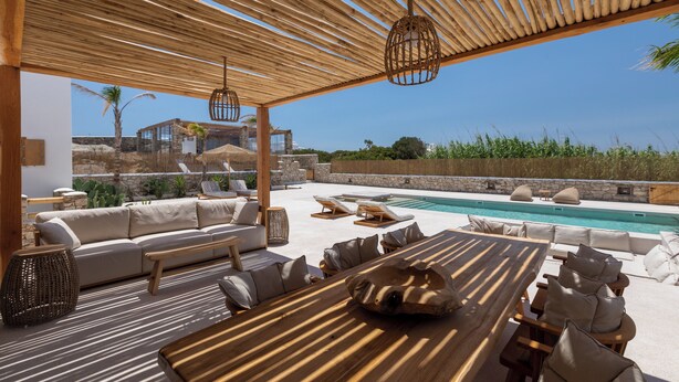 An outdoor lounge area with a pool, wooden pergola, and seating arrangements. - Cocopalm Villas Naxos (Naxos)