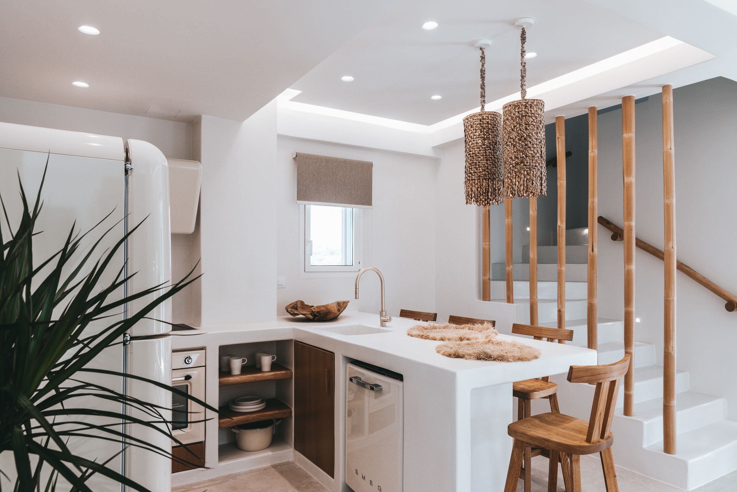 Une cuisine moderne avec un îlot central blanc, des chaises en bois et un luminaire suspendu.