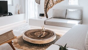 A modern living room with a round wooden coffee table, a sofa, a chair, and a TV. - Cocopalm Villas Naxos (Naxos)