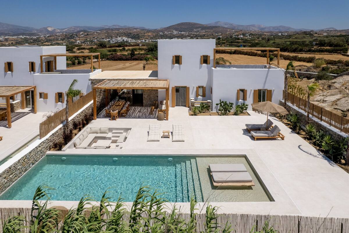A modern villa with a swimming pool, outdoor seating, and a view of the surrounding landscape.