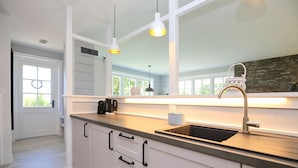 A modern kitchen with white cabinetry, a black countertop, and pendant lighting. - Redewisch vacation apartment " Lee " (Boltenhagen/Redewisch)