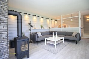 Ein modernes Wohnzimmer mit einem schwarzen Kaminofen, einem grauen Ecksofa und einem weißen Couchtisch.