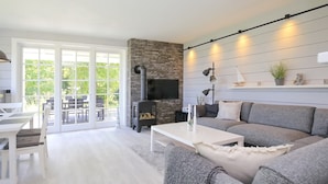 A modern living room with a fireplace, a sofa, a coffee table, and a dining area with chairs and a table. - Redewisch vacation apartment " Lee " (Boltenhagen/Redewisch)