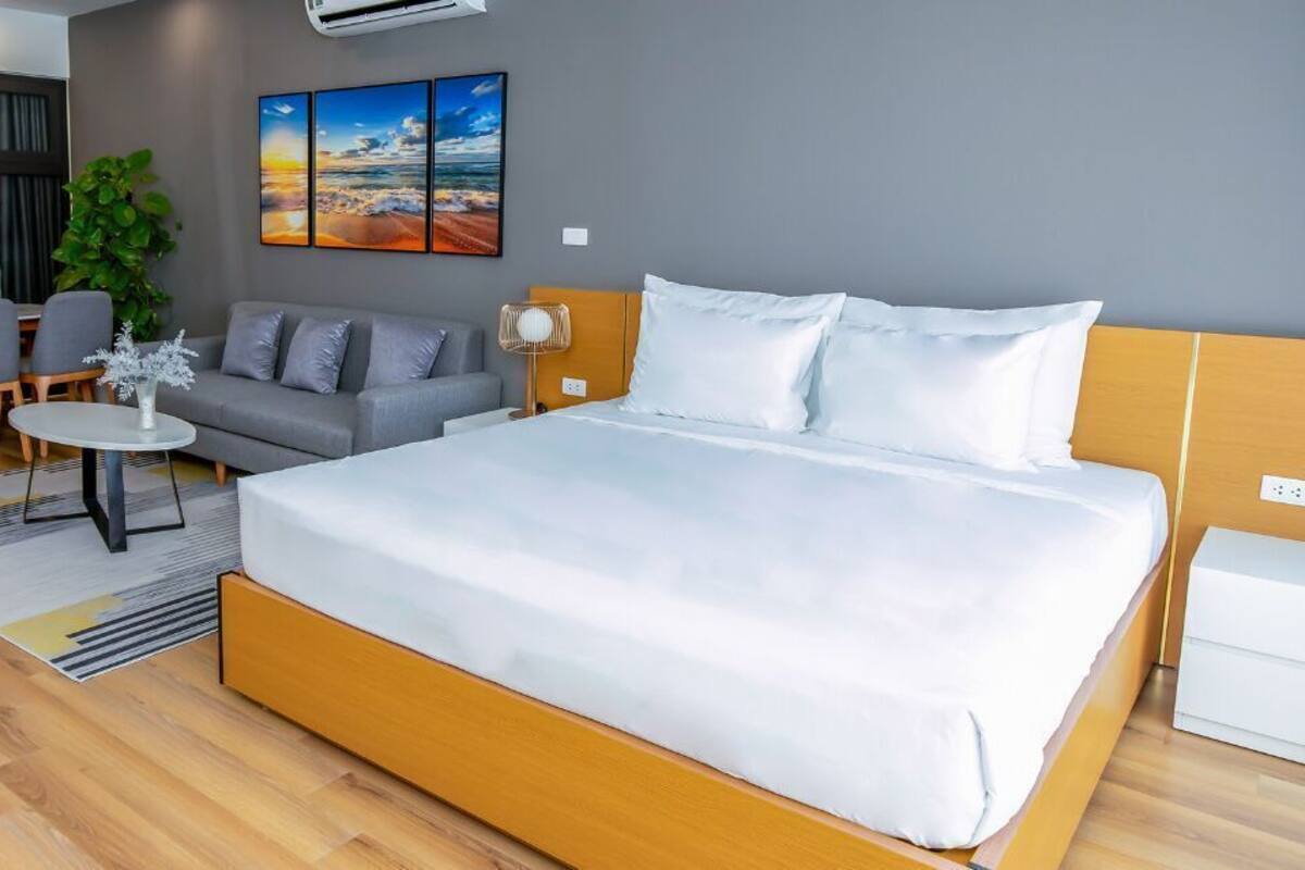 A hotel room with a large bed, a sofa, a small table, and a desk.