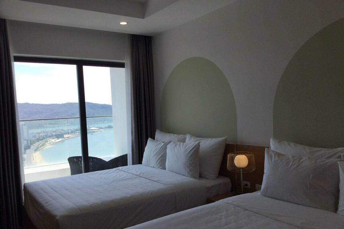 A hotel room with two beds, a view of a body of water, and a chair.