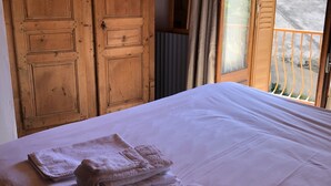 A bedroom with a large bed, wooden wardrobe, and a balcony with curtains.