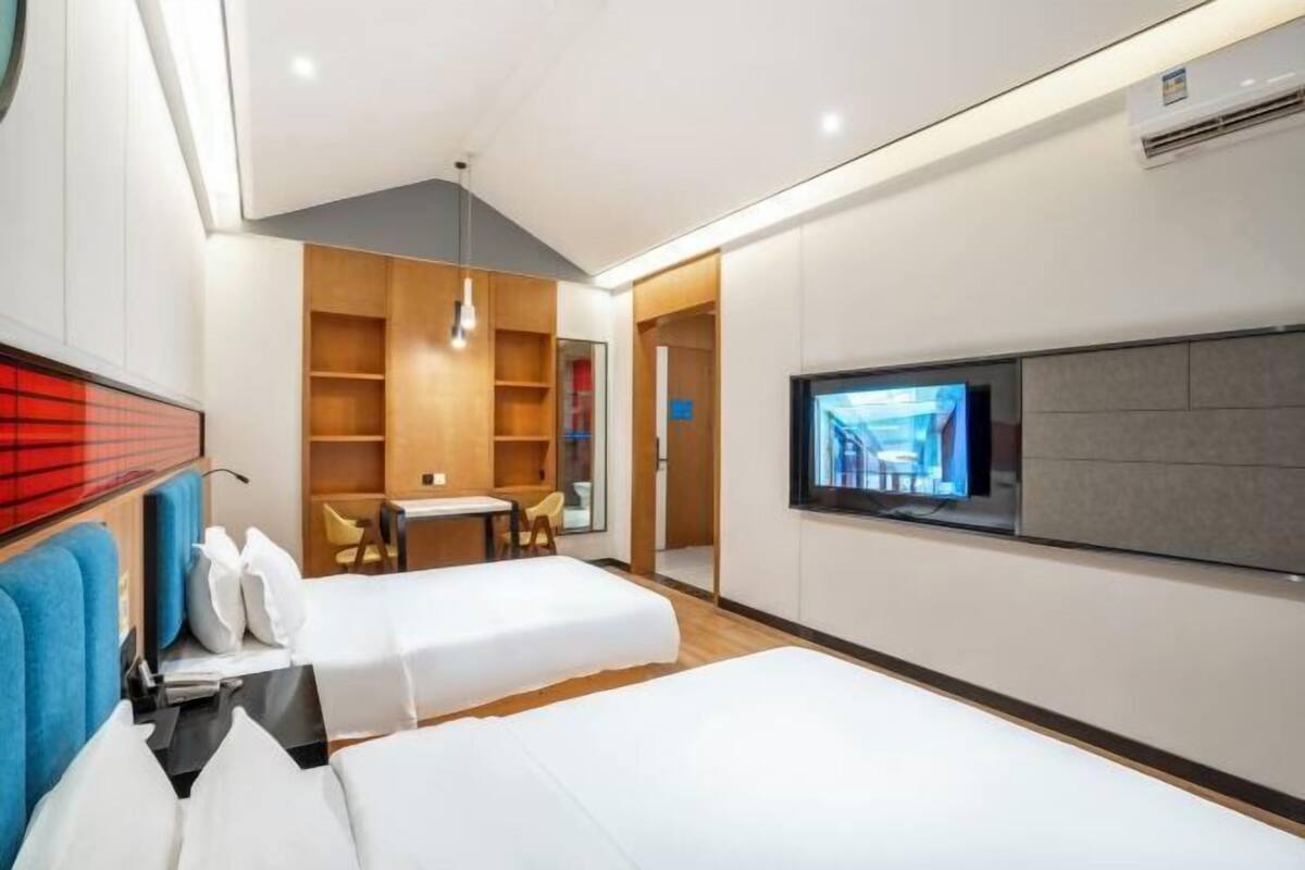 Une chambre d’hôtel moderne équipée de deux lits, d’une télévision, d’un bureau et d’un coin salon.