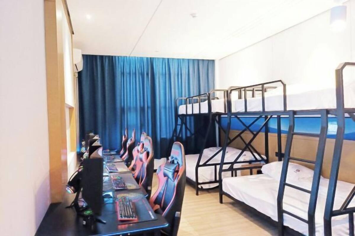 Une chambre avec des lits superposés, un bureau avec une chaise et un ordinateur.