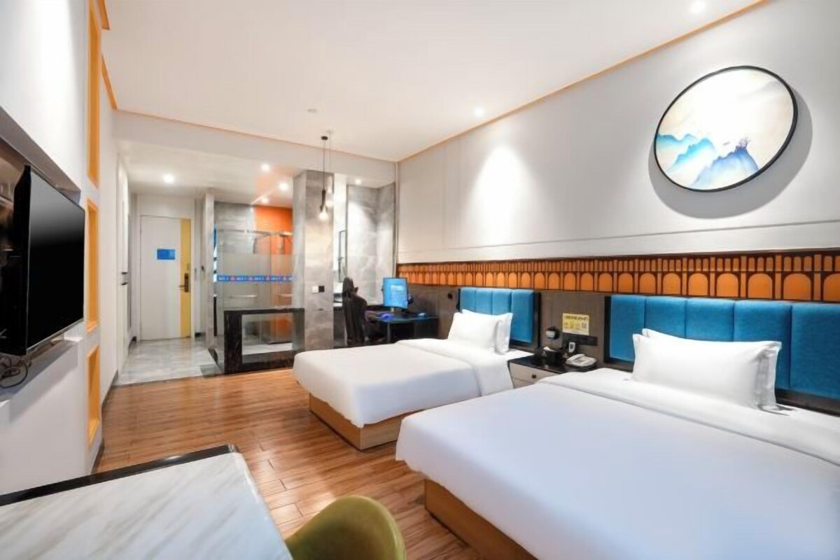 Een hotelkamer met twee bedden, een televisie, een bureau en een badkamer.
