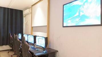 A conference room with multiple computer monitors, a projector screen, and ergonomic chairs.