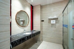 Un bany modern amb un sollloc de marbre, un mirall rodó i una cabina de dutxa de vidre.
