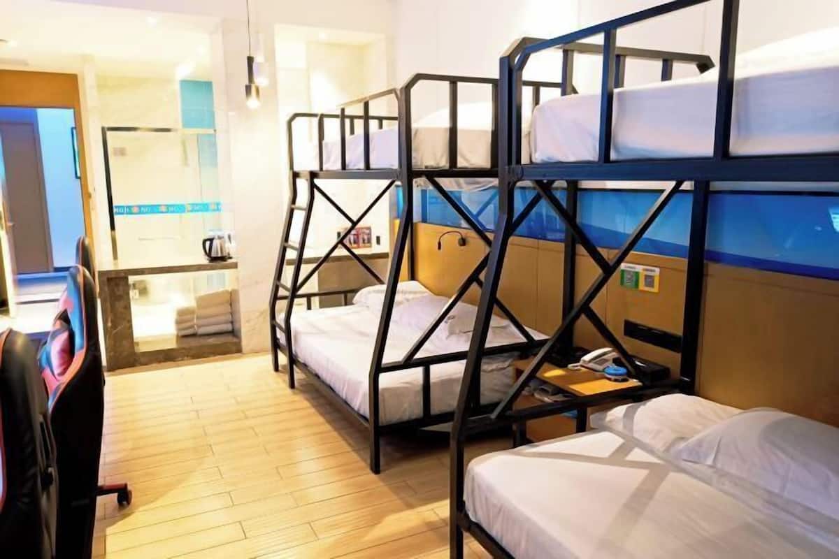Une chambre d’hôtel avec des lits superposés, un bureau avec un téléphone et une salle de bain visible.
