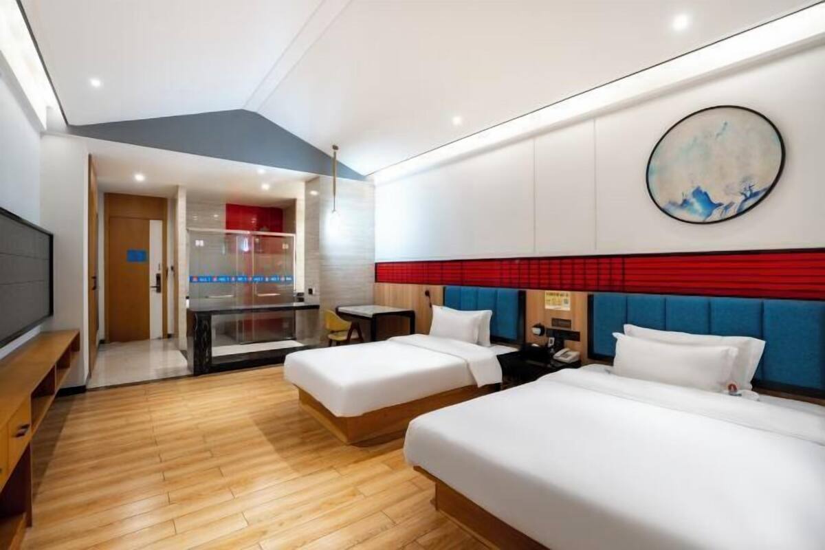 Une chambre d’hôtel avec deux lits, un bureau et une télévision.