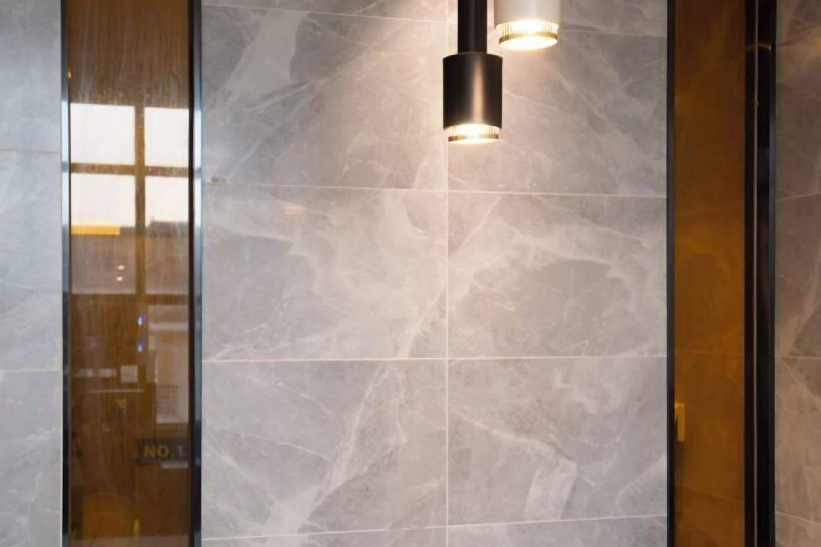 A modern interior with marble walls and a glass door with a sign.