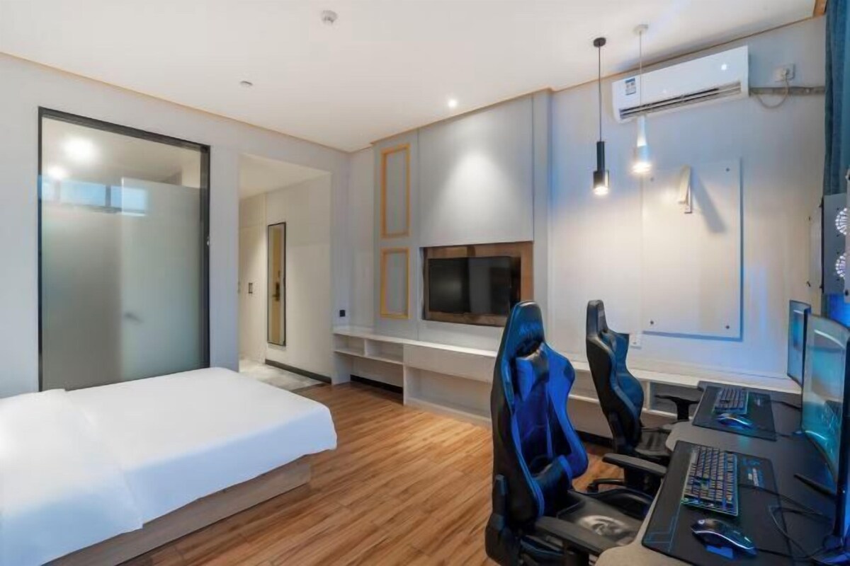 Camera d'albergo moderna con un letto, una scrivania con un computer, una TV e un'area salotto.