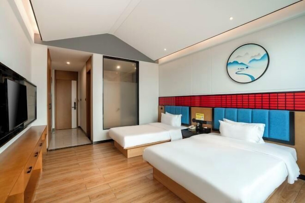 Una camera d'albergo con due letti, una televisione e un quadro appeso al muro.