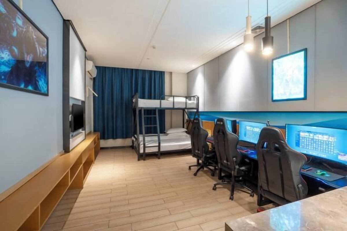 Une chambre avec des lits superposés, un bureau avec des ordinateurs et une télévision.
