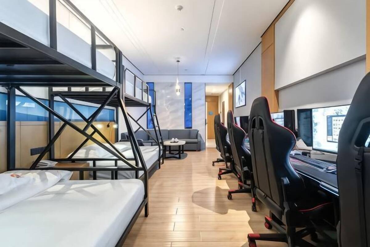 Une chambre d’hôtel moderne équipée de lits superposés, d’un canapé, de fauteuils de jeu et d’un bureau avec un ordinateur.
