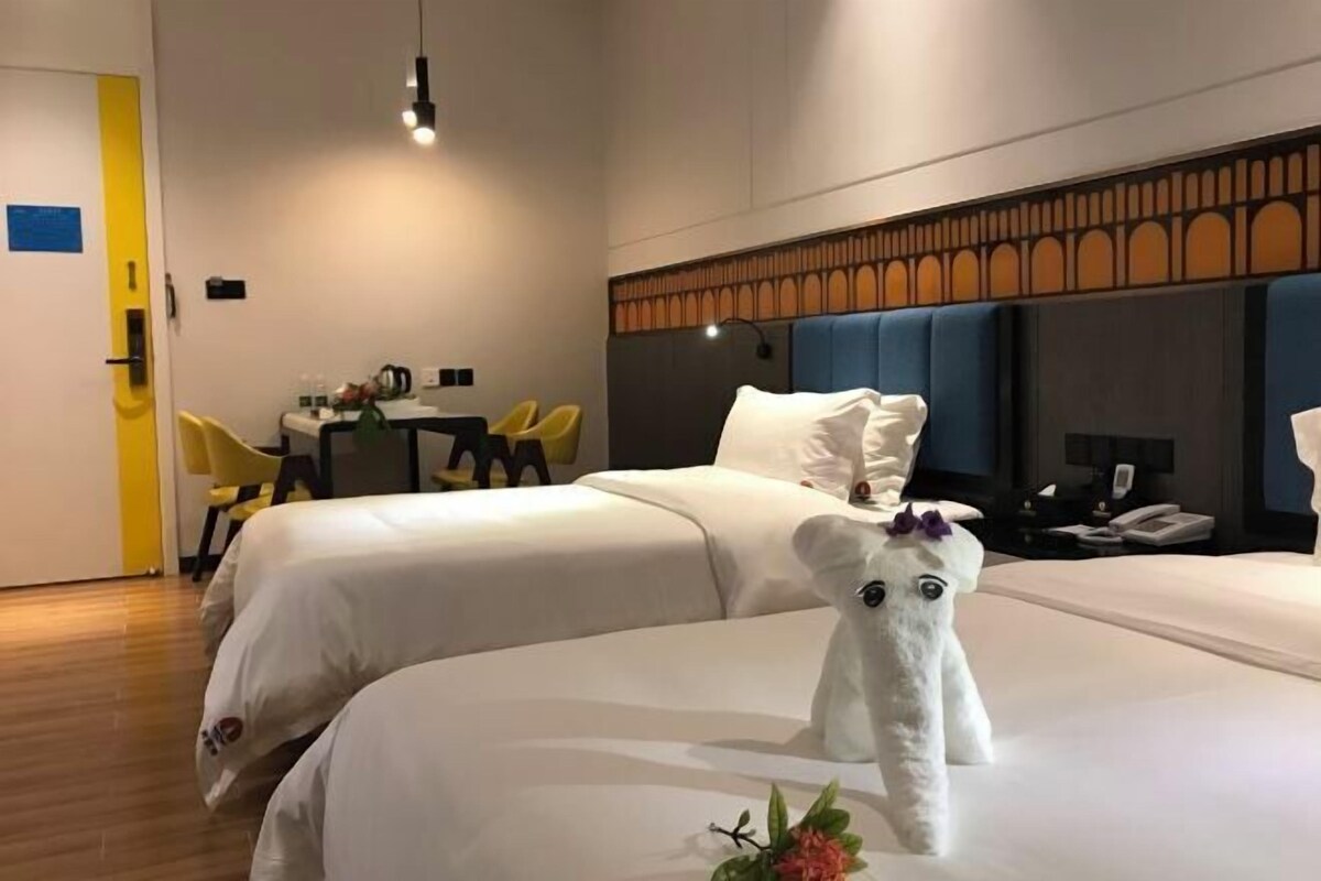 Una camera d'albergo con due letti, una scrivania e delle sedie.