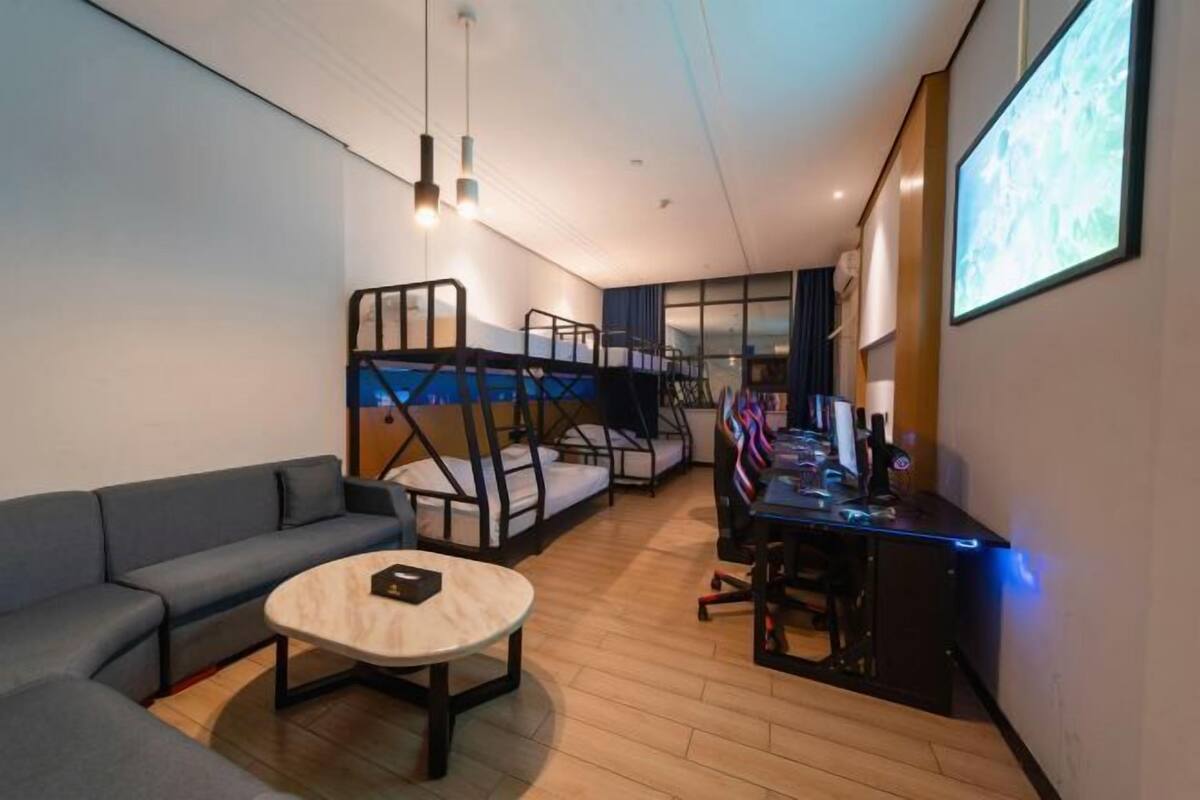 Une chambre moderne avec un canapé, une table basse ronde, un bureau avec un ordinateur et un lit superposé.