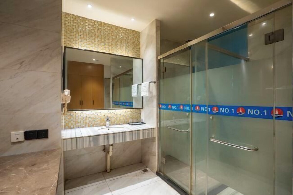 Un bagno moderno con cabina doccia in vetro, lavandino con specchio sopra e schienale in piastrelle.