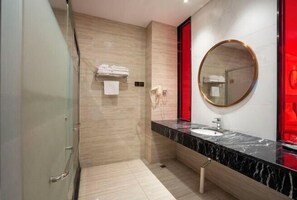 Un bany modern amb un lavabo de marbre, un mirall rodó i un suport per a tovalloles.