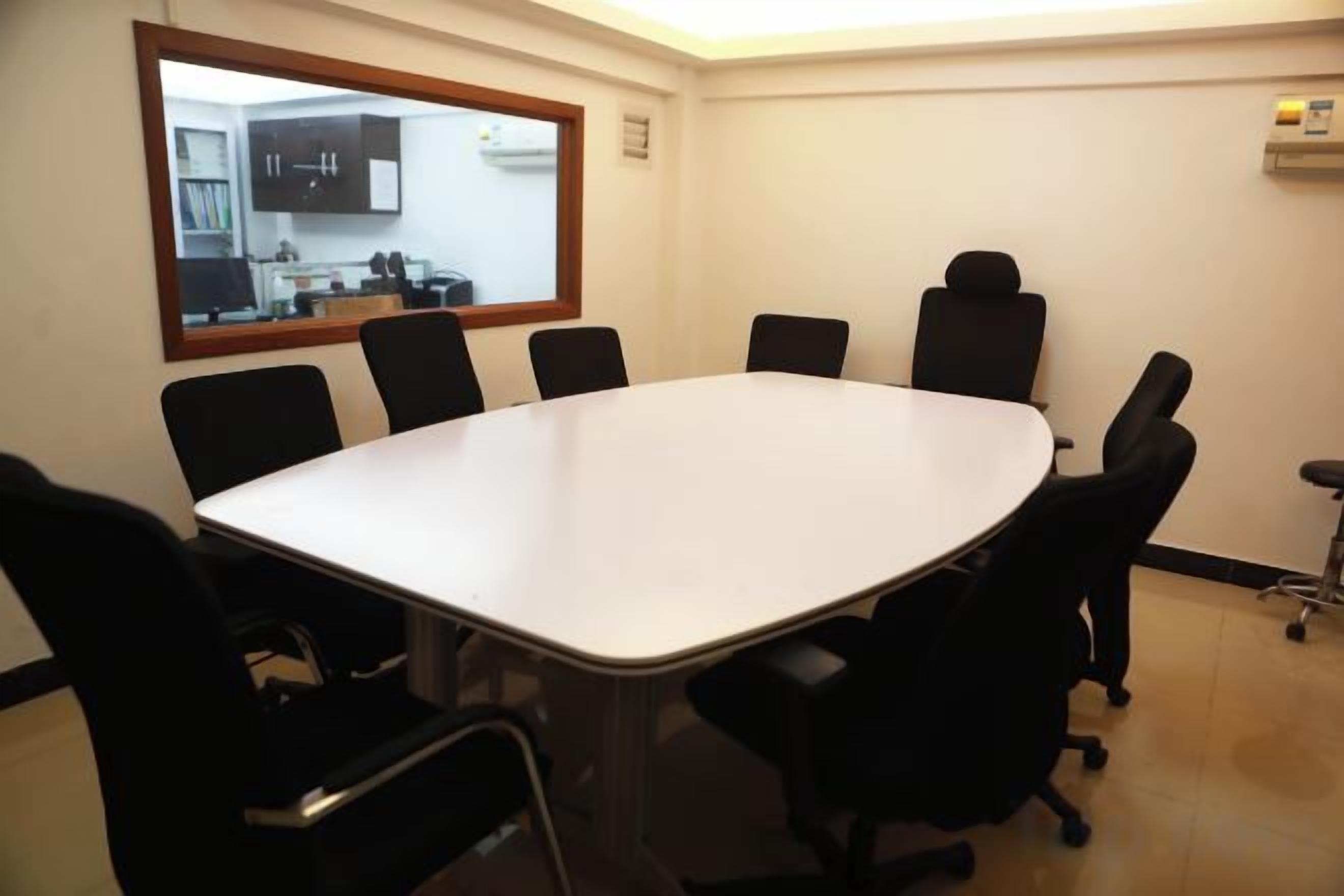 A conference room with a large table and six chairs.