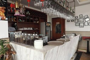 A bar area with a marble counter, shelves with bottles, and hanging glasses. - Hai Run Business Hotel (Taishan)