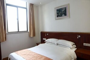 Una habitación de hotel con una cama, una mesita de noche, una ventana con cortinas y un cuadro en la pared.