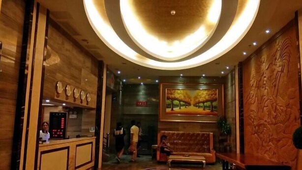Un hall con mostrador de recepción, un área de estar con sofá y un cuadro grande en la pared.