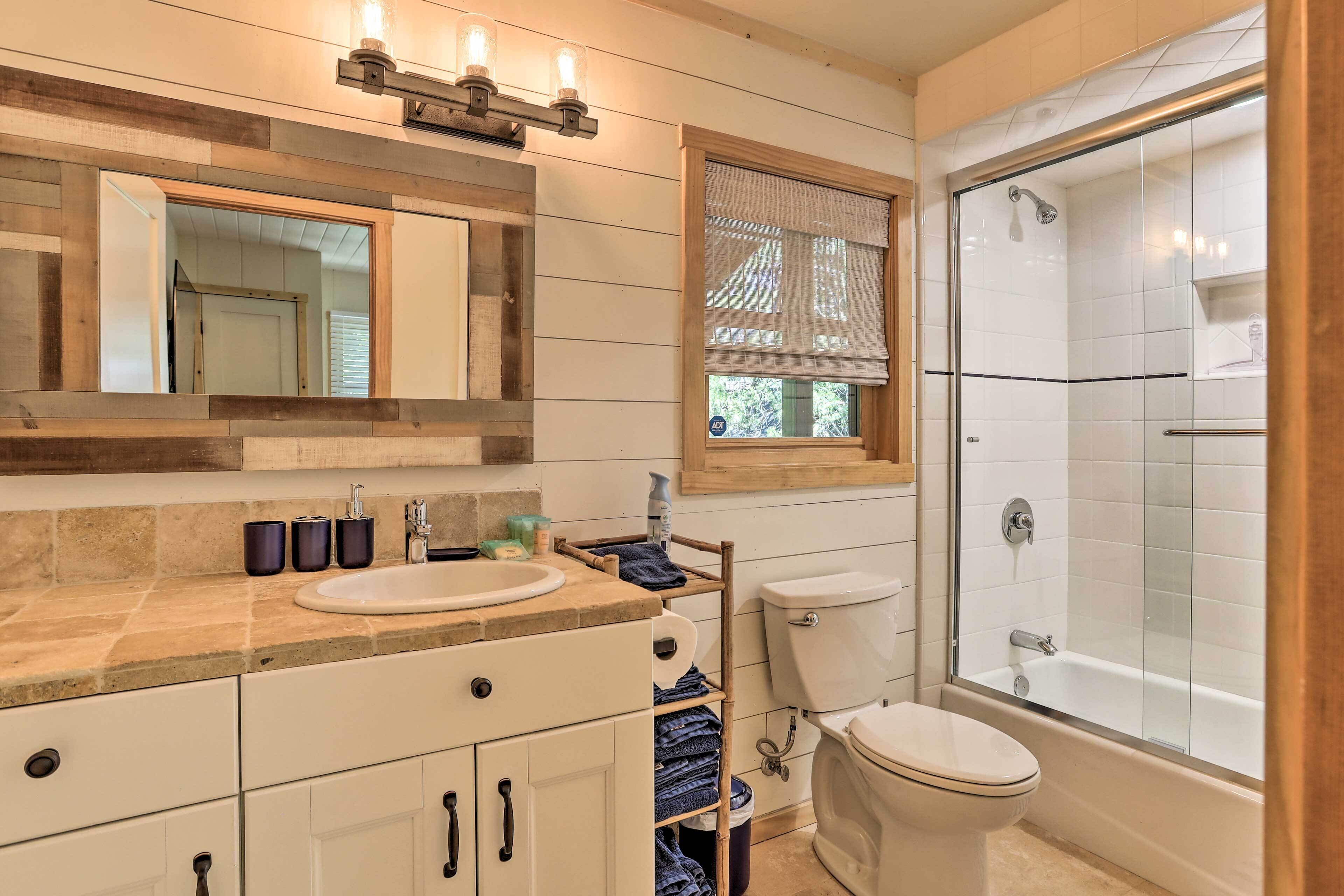 Une salle de bain équipée d’un lavabo, de toilettes et d’une douche à parois de verre.