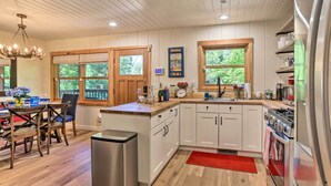 A modern kitchen with wooden cabinets, a stainless steel refrigerator, and a red rug. - Steps to Lake: Cabin w/ Deck in Lake Arrowhead (Lake Arrowhead)